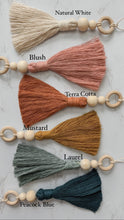 Load image into Gallery viewer, Six hanging tassel charms with wooden beading detail shown in white, blush, terra cotta, mustard, teal, and blue colors 
