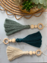 Load image into Gallery viewer, Three hanging tassel charms with wooden beading detail shown in white, teal, and blue colors 
