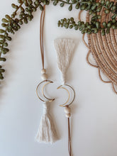 Load image into Gallery viewer, Two gold crescent moon charms with cotton tassels 
