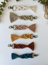 Load image into Gallery viewer, Six  6-inch macrame keychains with gold keychain ring and clasp seen in natural white, oatmeal, mustard yellow, rust, and peacock blue cotton
