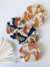 Load image into Gallery viewer, Two white, pink, and yellow macrame coasters, and two beige, blue, and terra cotta macrame coaster
