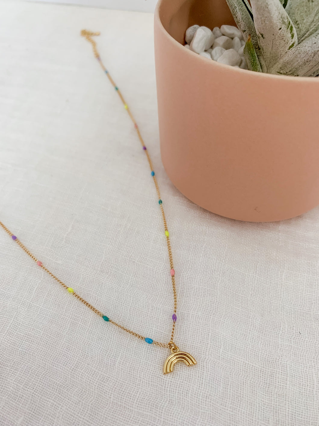 A gold plated epoxy pastel chain with clasp adorned with a gold rainbow charm 