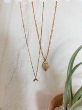 Load image into Gallery viewer, A gold plated epoxy pastel chain with clasp adorned with a gold rainbow charm seen by another gold necklace
