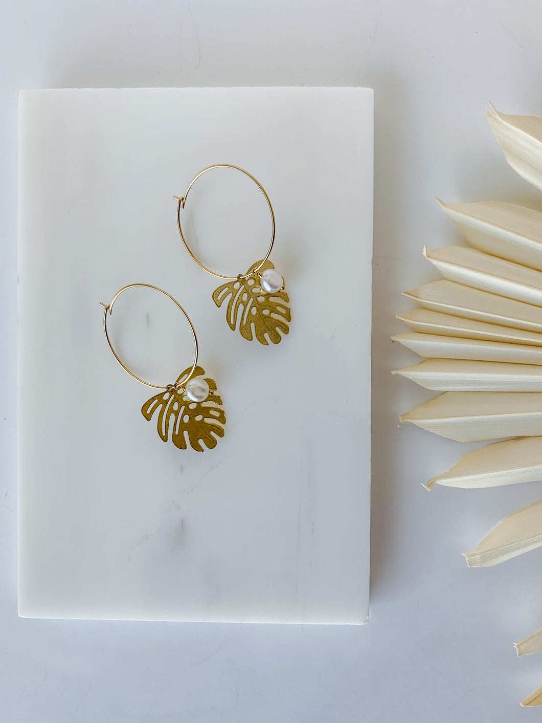 A pair of gold plated 30mm hoop earrings with gold plated monstera charm and freshwater pearl 
