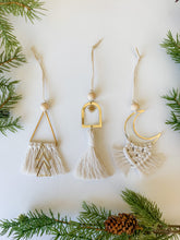 Load image into Gallery viewer, Three ornaments with brass rings in moon shape, triangle shape, and sunburst charm with macrame cord tassels. 
