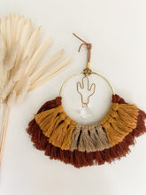 Load image into Gallery viewer, A macrame suncatcher with gold cactus charm and mix of maroon, mustard yellow, and tan cotton fringe

